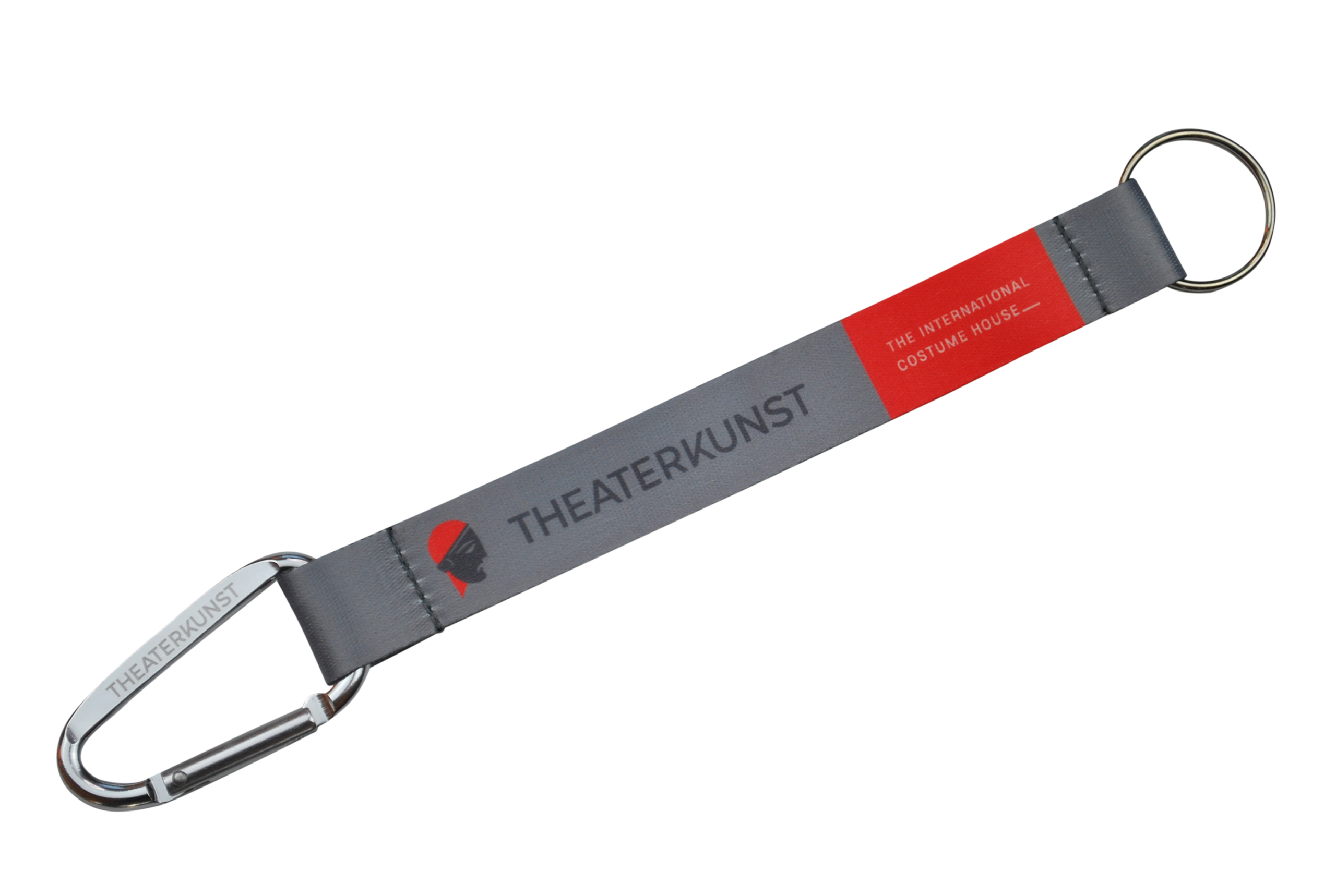 Grauer Schlüsselanhänger mit Karabiner, bedruckt mit „THEATERKUNST“ und „THE INTERNATIONAL COSTUME HOUSE“.